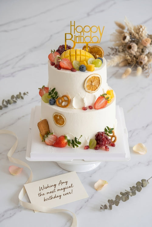 Close-up on two-tier white buttercream cake featuring fresh fruit decorations
