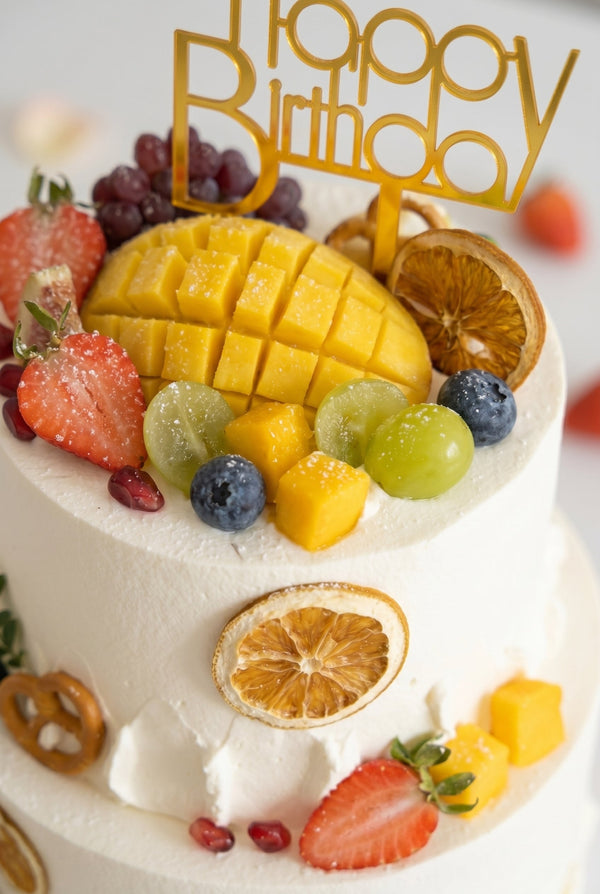 Two-tier white buttercream cake decorated with fresh strawberries, grapes, and blueberries