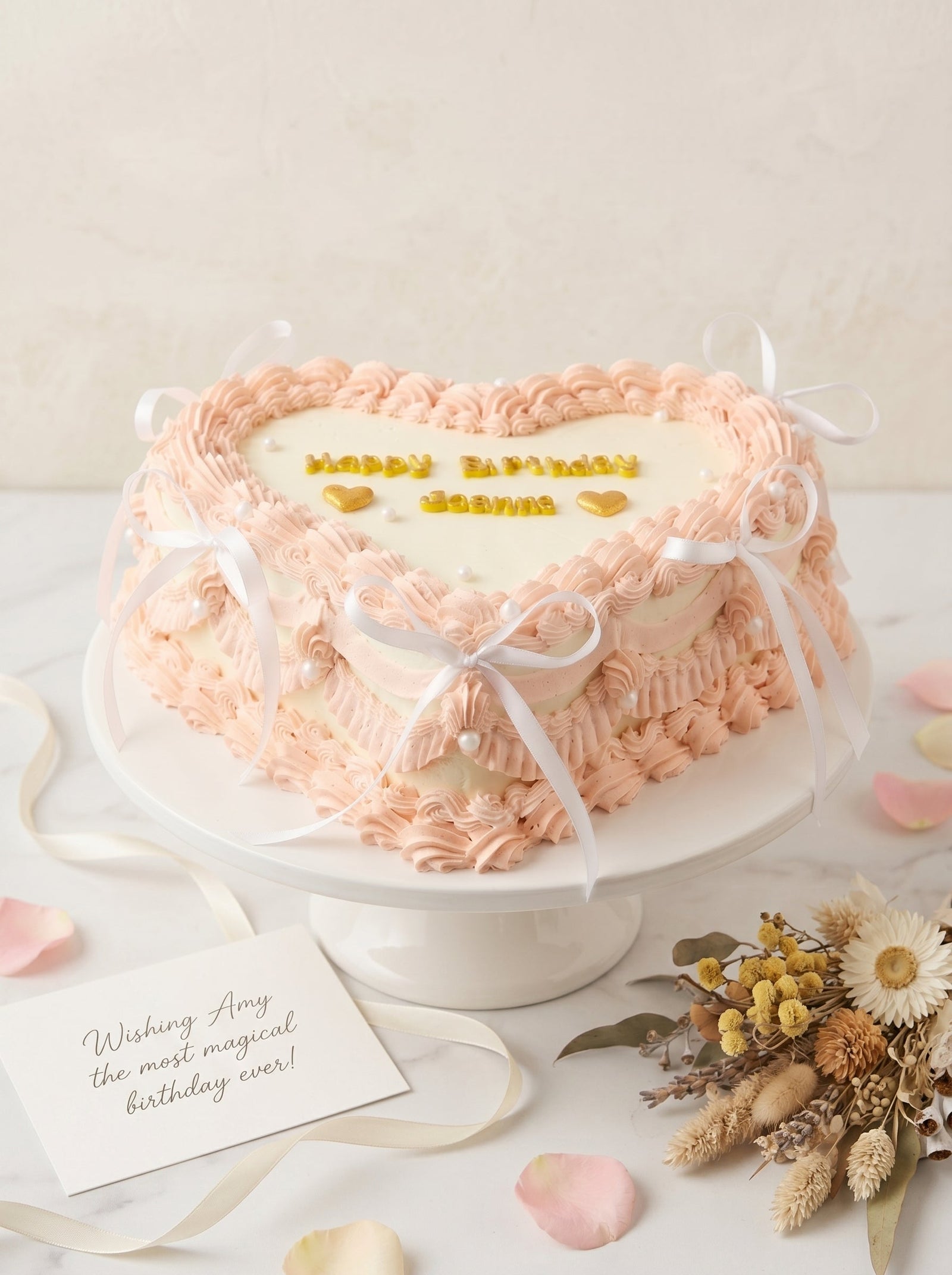 Close-up of an elegant heart-shaped cake featuring pink piped buttercream borders, white center panel, and pearl accents.