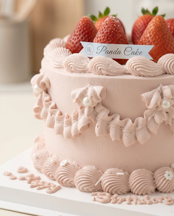 Top view of round pink cream cake with strawberry decoration and elegant cream piping
