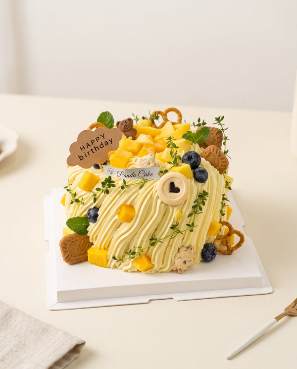 Studio hero photo of square birthday cake with pale cream frosting and piped ridges topped with mango cubes and edible decorations