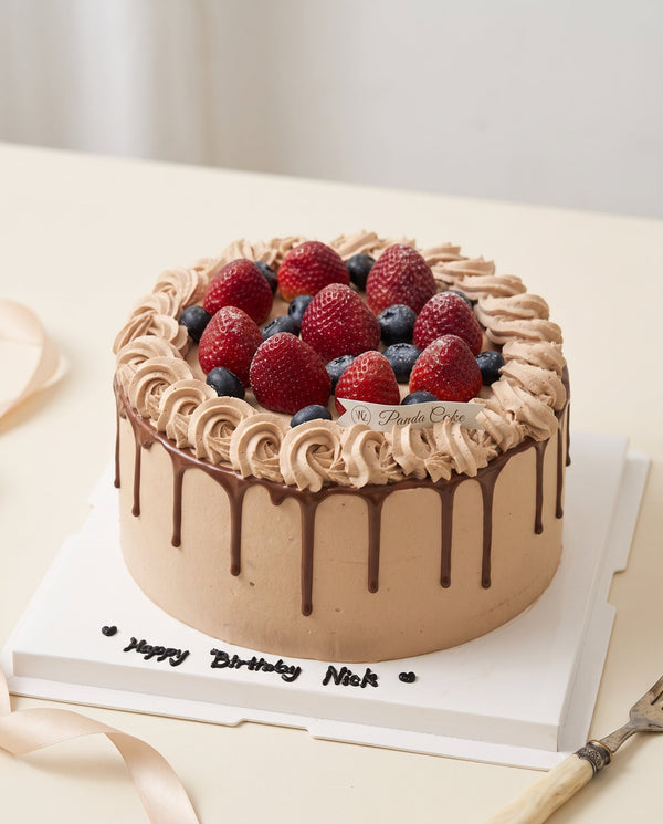 Studio product-hero photo of a round chocolate drip cake with taupe brown buttercream rosettes and glossy chocolate drips
