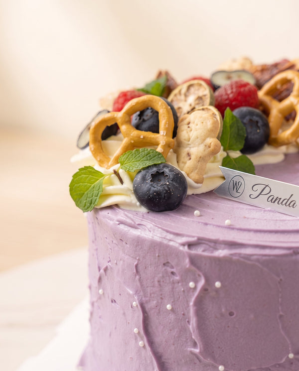 Close-up of round tall lavender buttercream birthday cake showing smooth swirled frosting and delicate pearl dragees