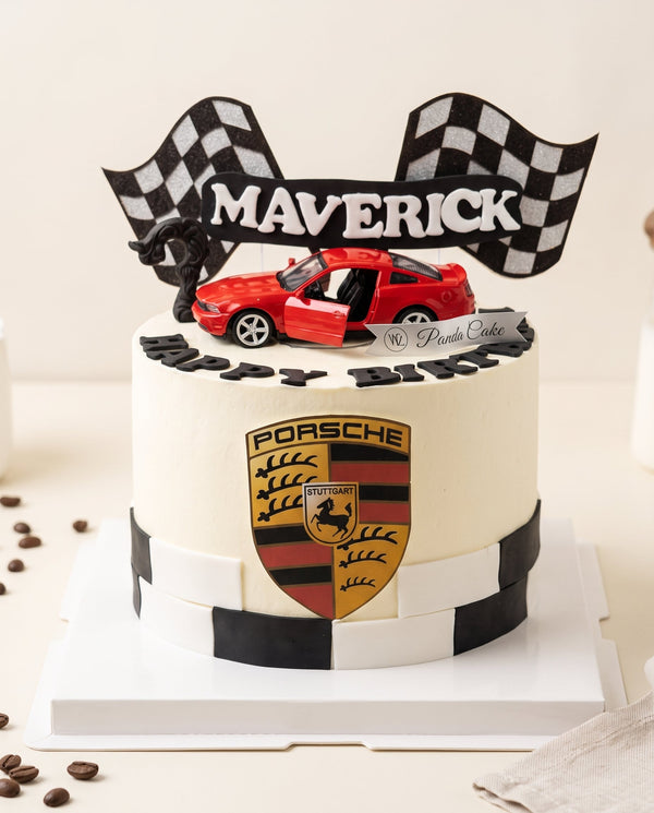 Round white-frosted racing cake with red sports car topper and checkered flags