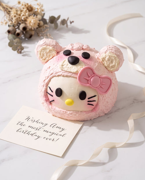 Close-up of pastel pink Hello Kitty bear-face cake showing white muzzle, black eyes and nose