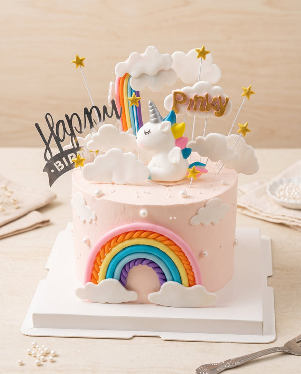 Studio photo of round pastel pink unicorn cake with smooth frosting and gold star toppers